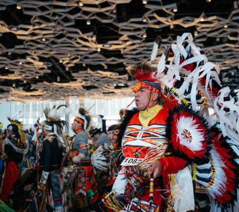 Une personne autochtone vêtue d'une coiffe traditionnelle danse avec d'autres personnes lors du pow-wow du festival Manito Ahbee.