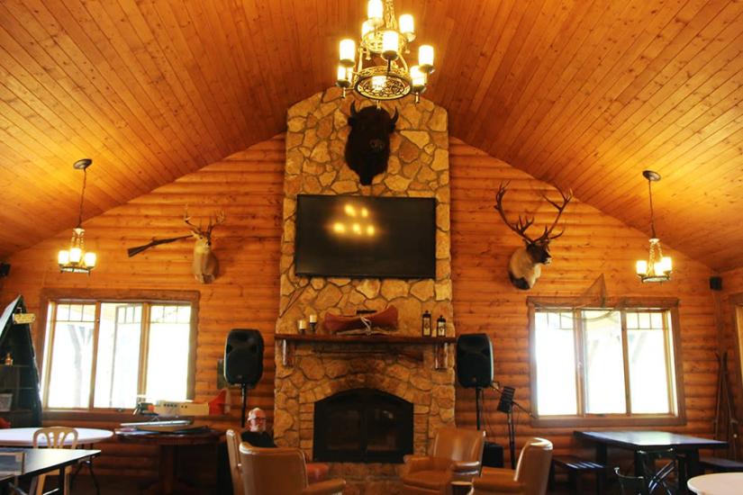 Intérieur du Bakers Narrows Lodge : Élégance rustique avec cheminée en pierre du sol au plafond, offrant un confort douillet dans la nature.