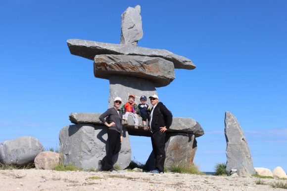 Une famille est assise sur un inuksuk de Churchill, profitant de la vue pittoresque sur l'extérieur dans un cadre culturel paisible.