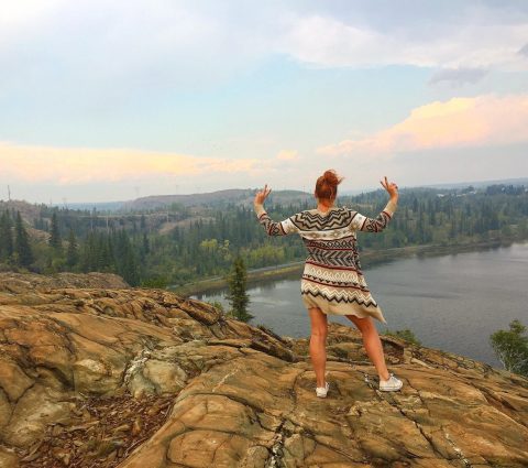 Personne posant au sommet d'une colline rocheuse surplombant la rivière près de Flin Flon.