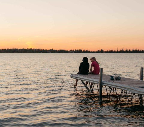 Enfants assis au bout d'un quai au coucher du soleil à The Pas, Manitoba