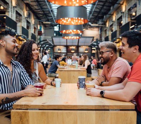 Quatre personnes dégustant des boissons, assises à une table au Common at The Forks
